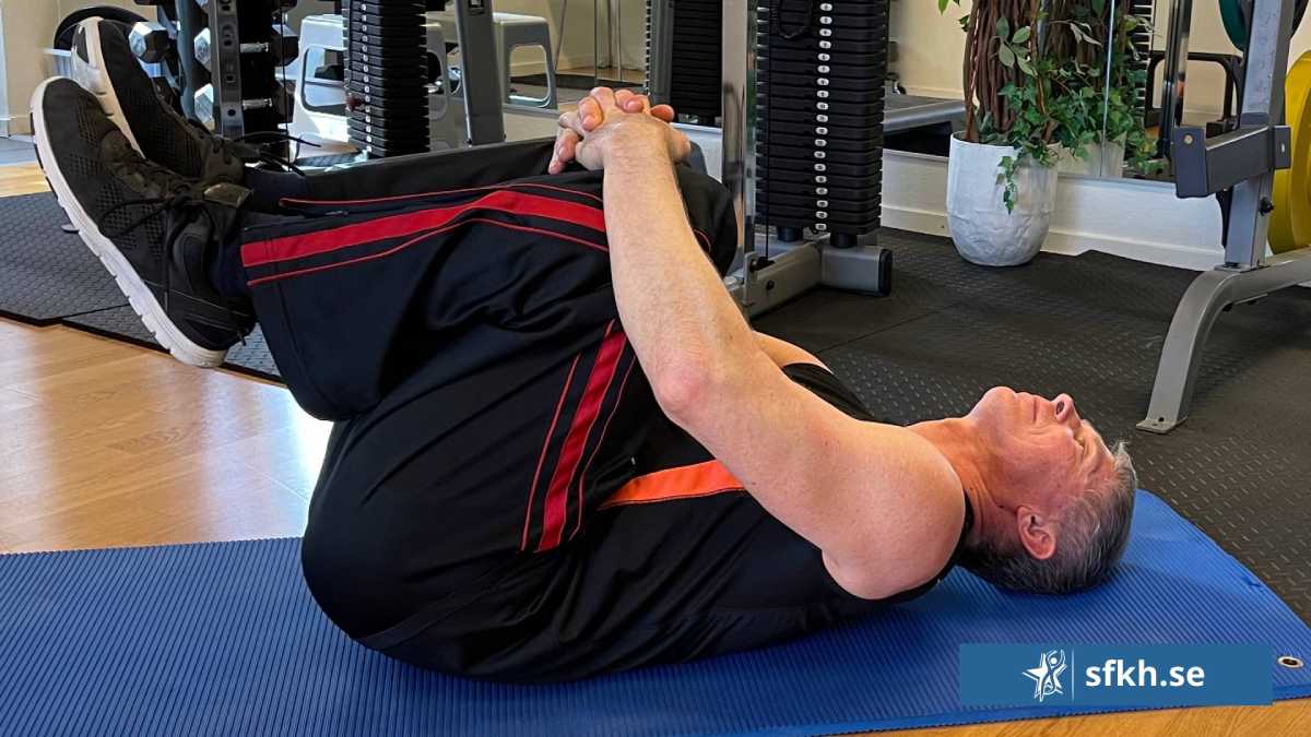sfkh-knana-mot-brostet-ryggliggandes Knäna mot bröstet ryggliggandes, en övning vid ryggskott
